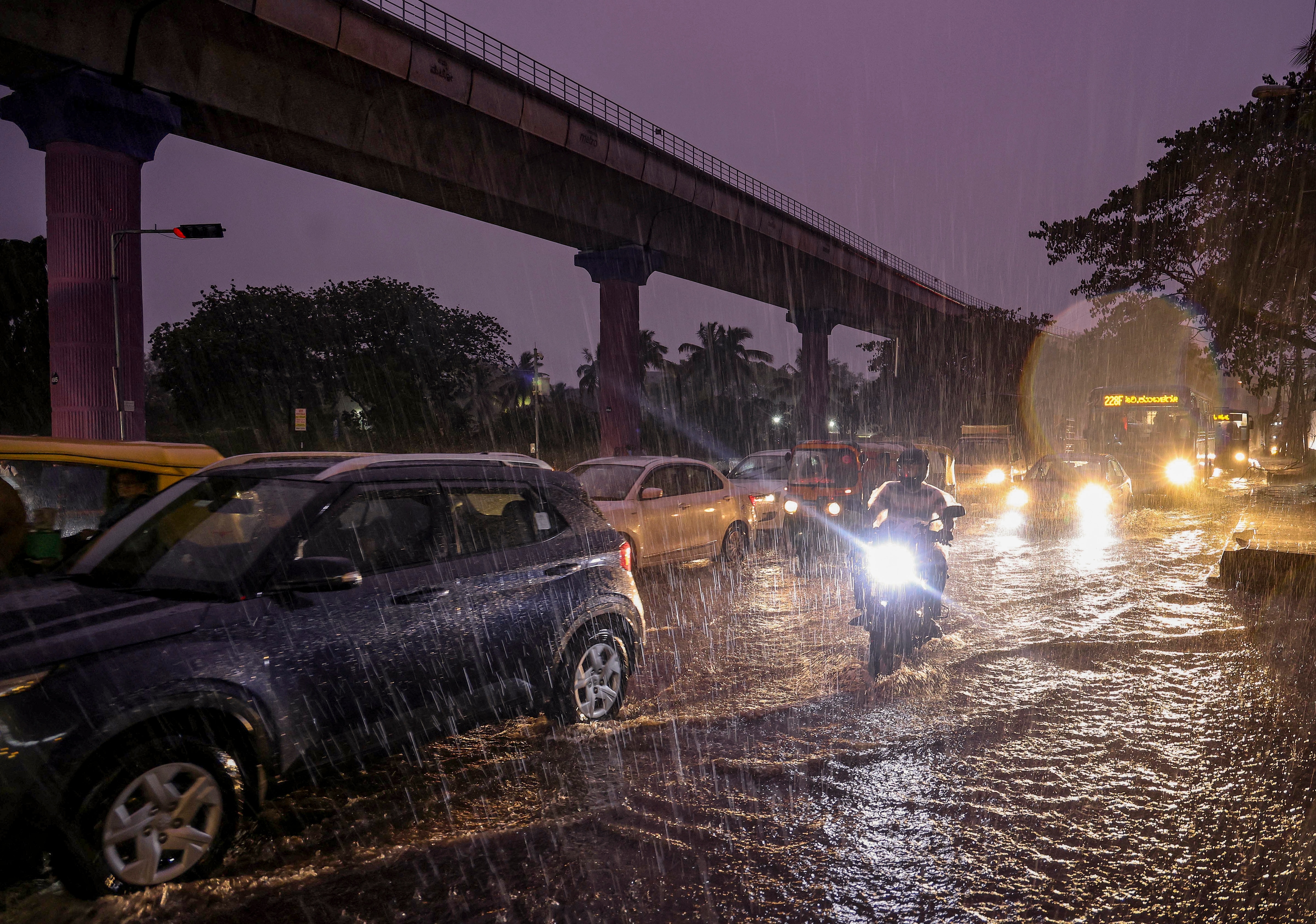 Commuters wade through a waterlogged road as rain lashes the city. (Photo: PTI)