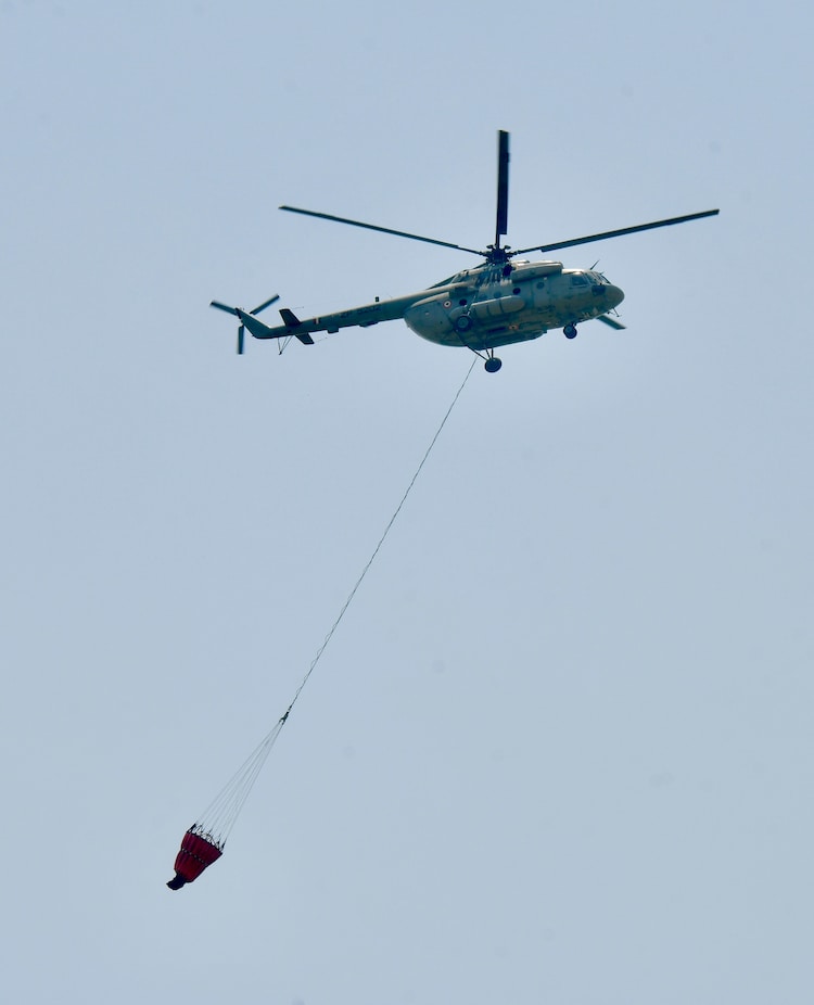 An Indian Air Force (IAF) helicopter collects water from Sukhna Lake for firefighting. (Photo: PTI)