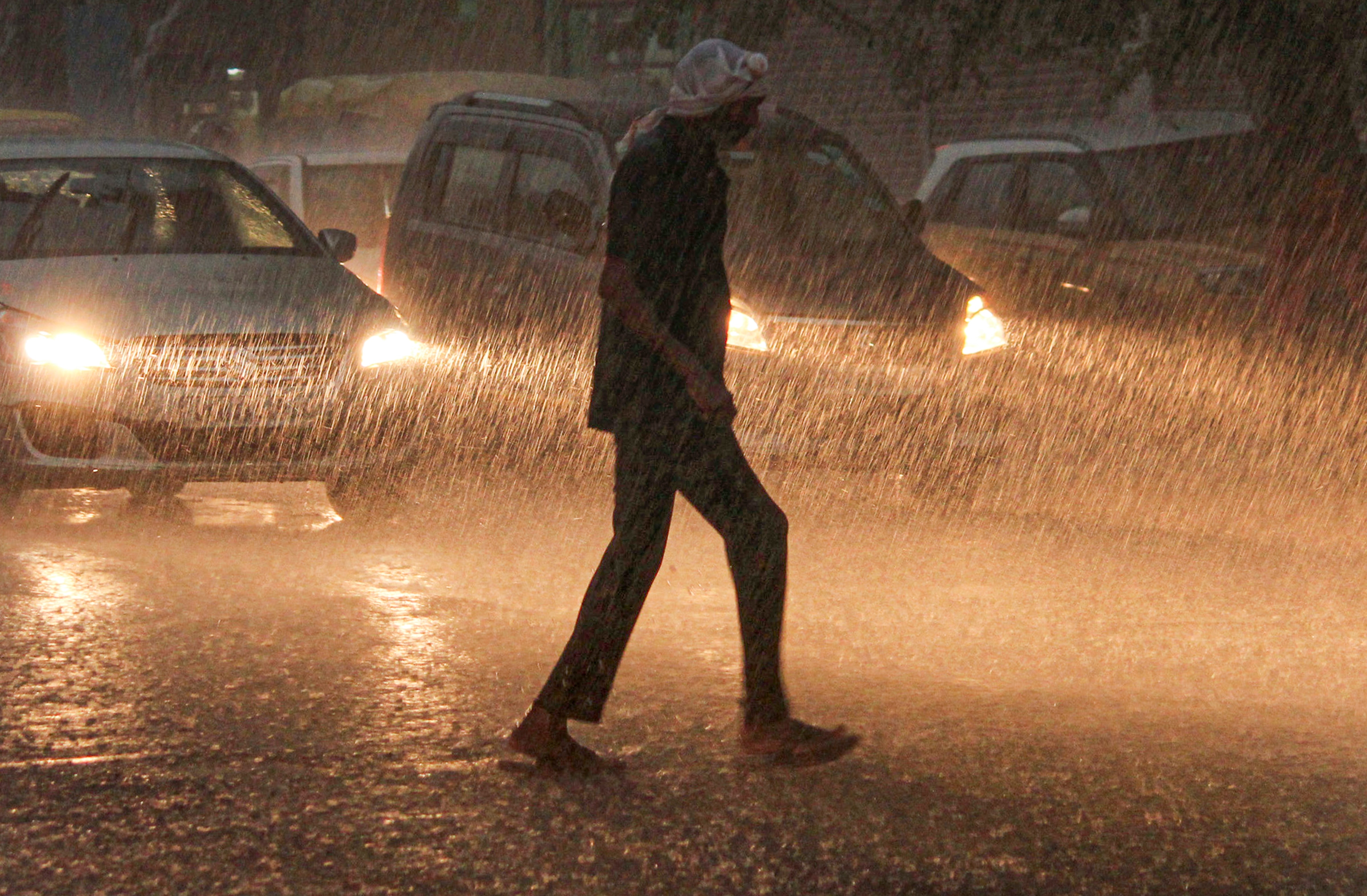 A man crosses a road amid rainfall, in Gurugram. (Photo: PTI)