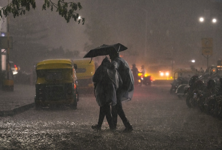 People cross a road amid heavy rain. (Photo: PTI)