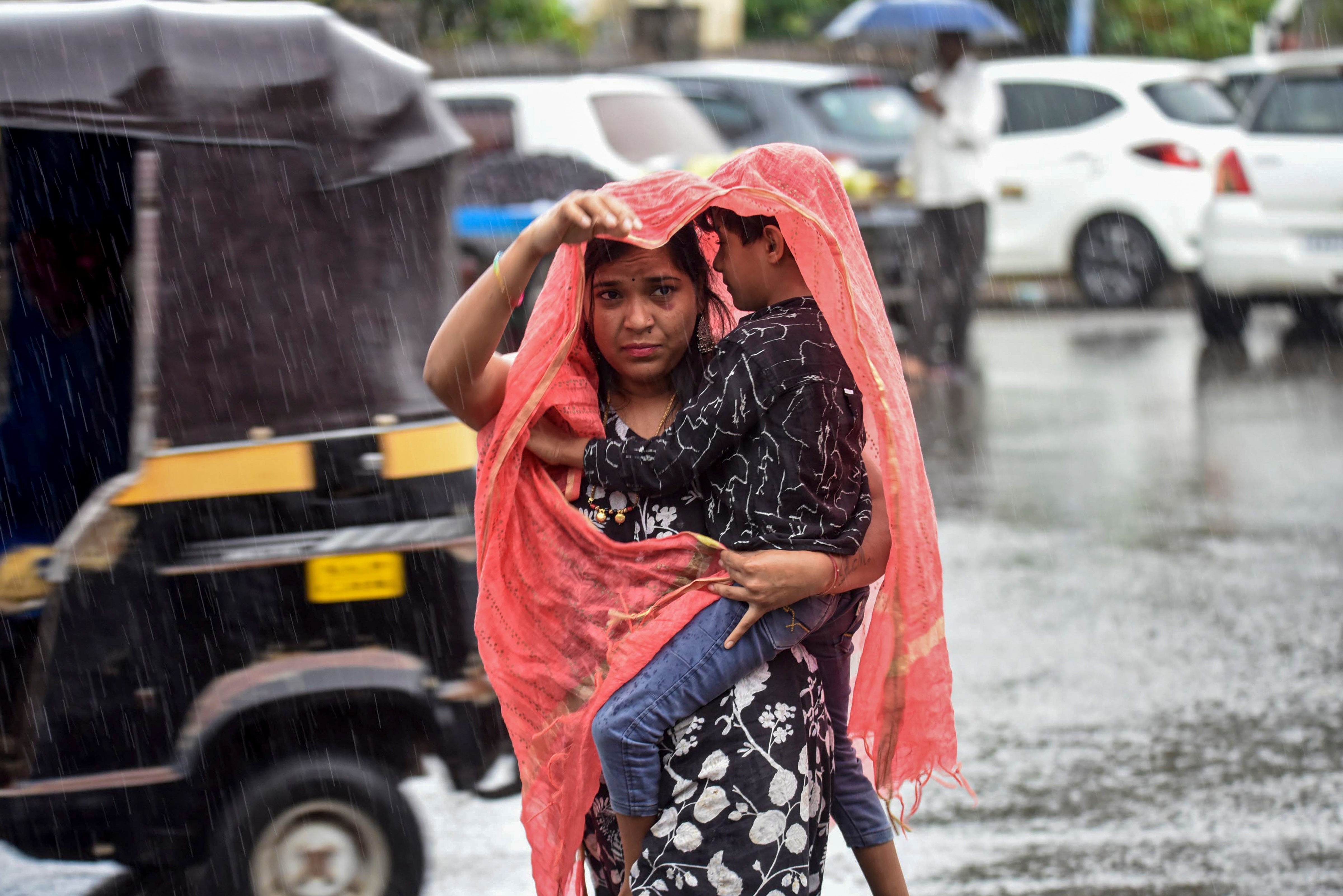 People cover themselves as they walk amid rainfall. (Photo: PTI)
