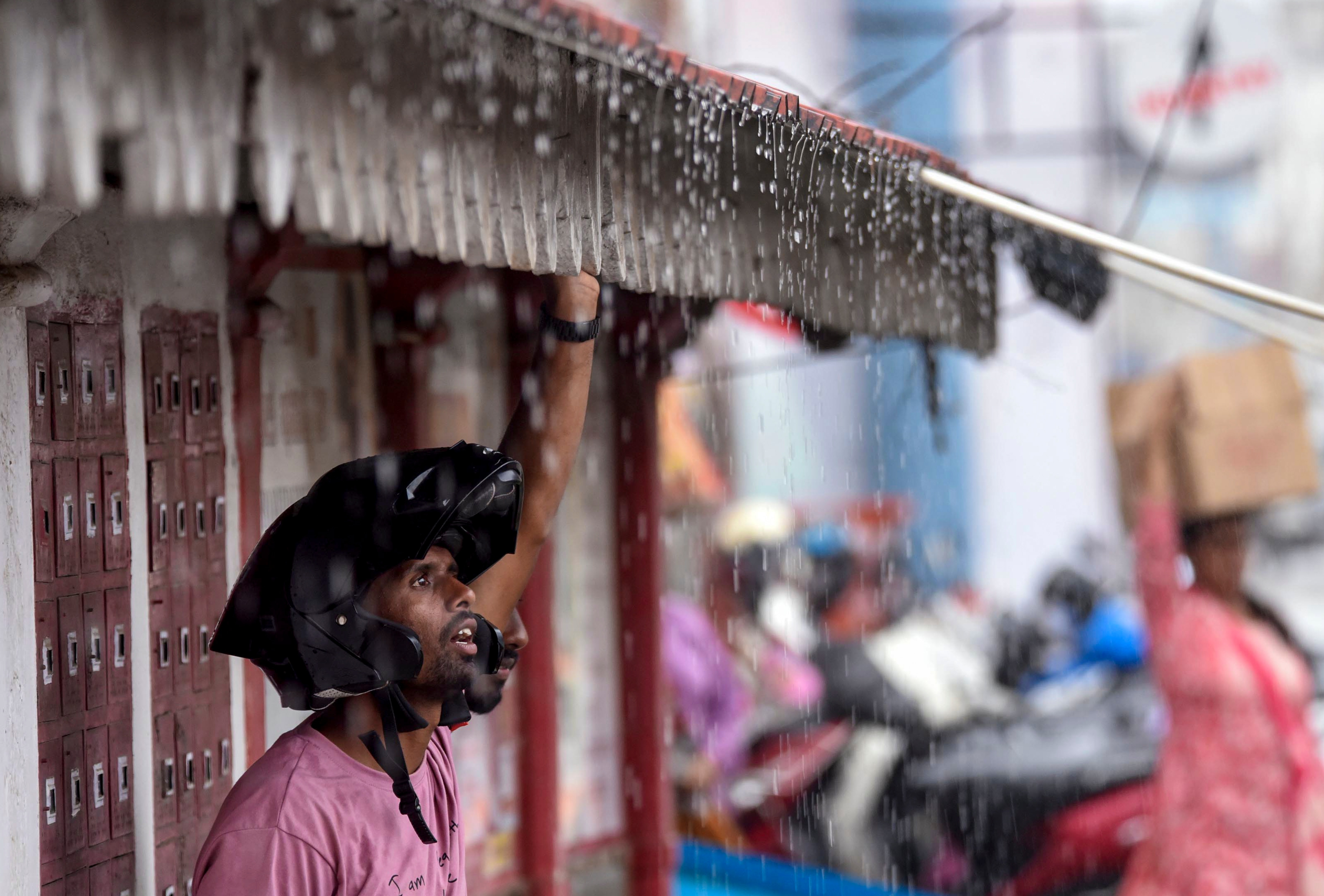 A man takes shade during a spell of heavy rain. (Photo: PTI)