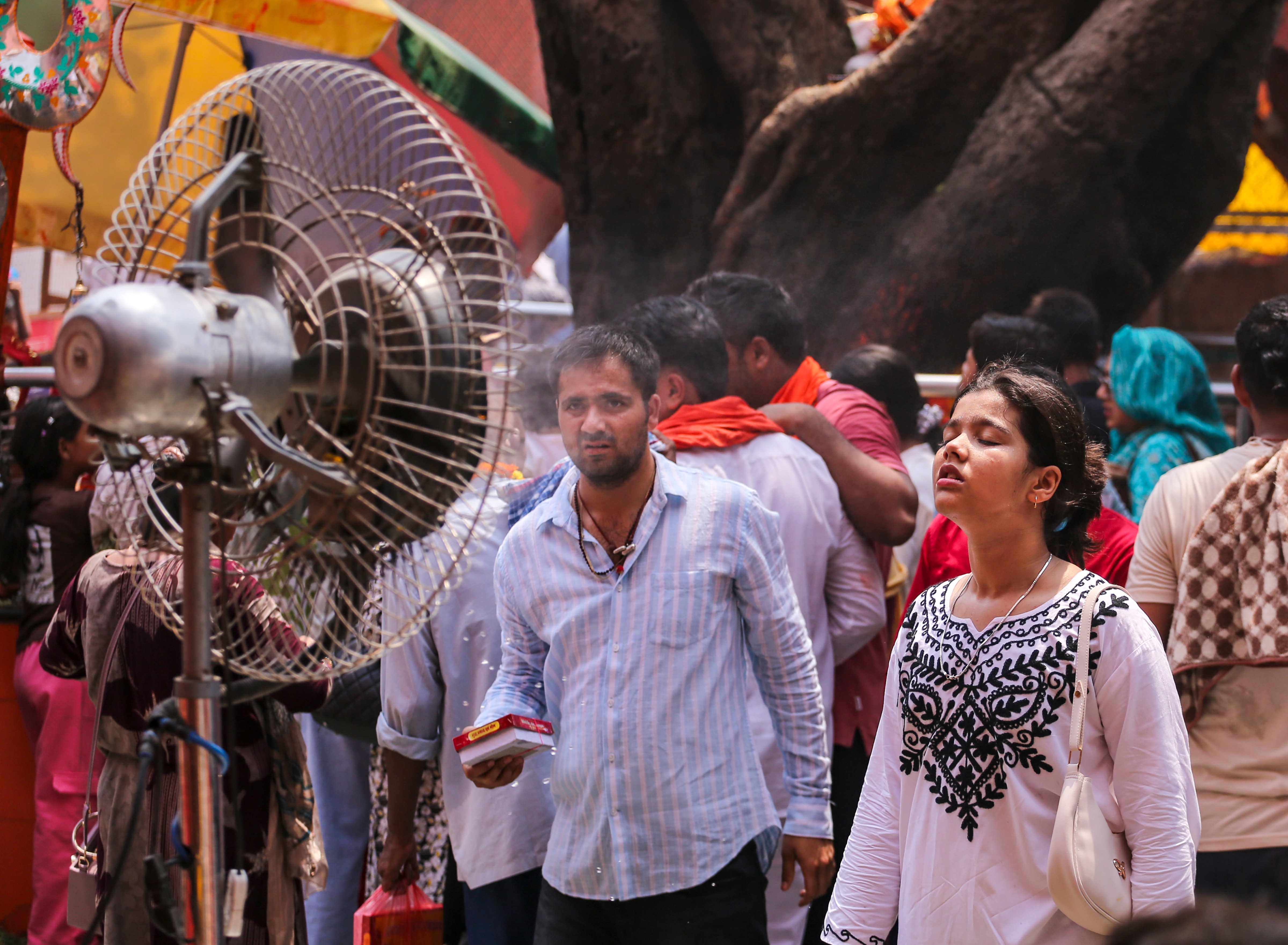 People stand in front of an air fan to protect themselves from the heat in UP. (Photo: PTI)