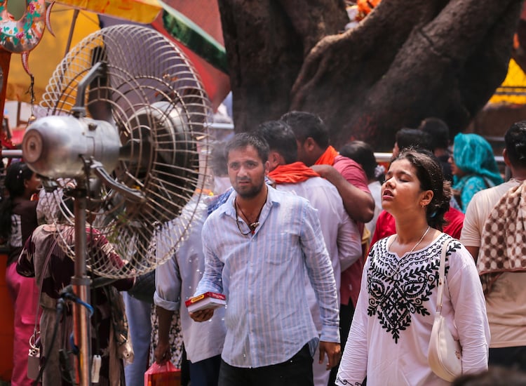 People stand in front of an air fan to protect themselves from the heat in UP. (Photo: PTI)