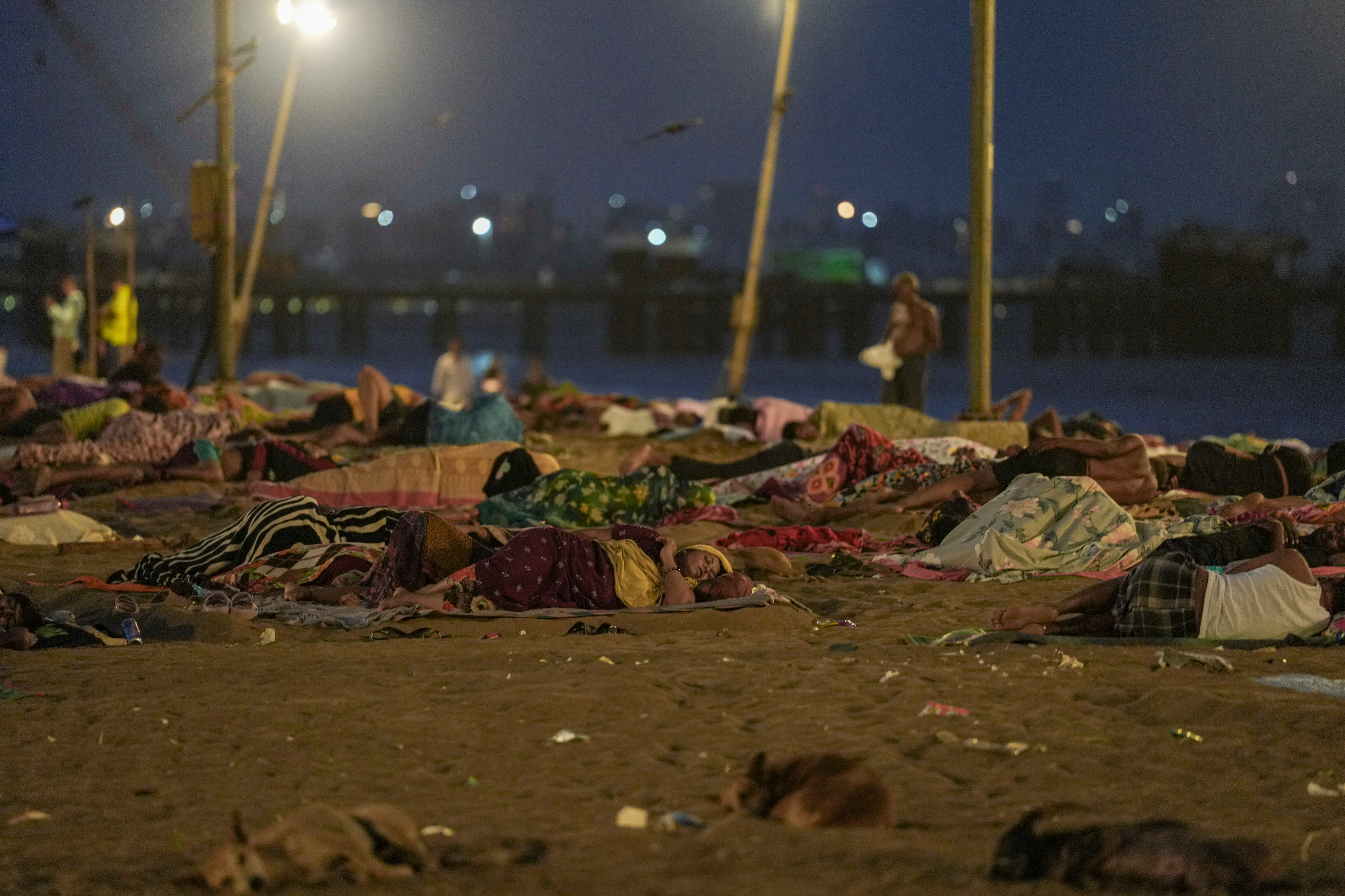 People sleep on Versova Beach amid intense heatwave and frequent power outages, in Mumbai. (Photo: PTI)