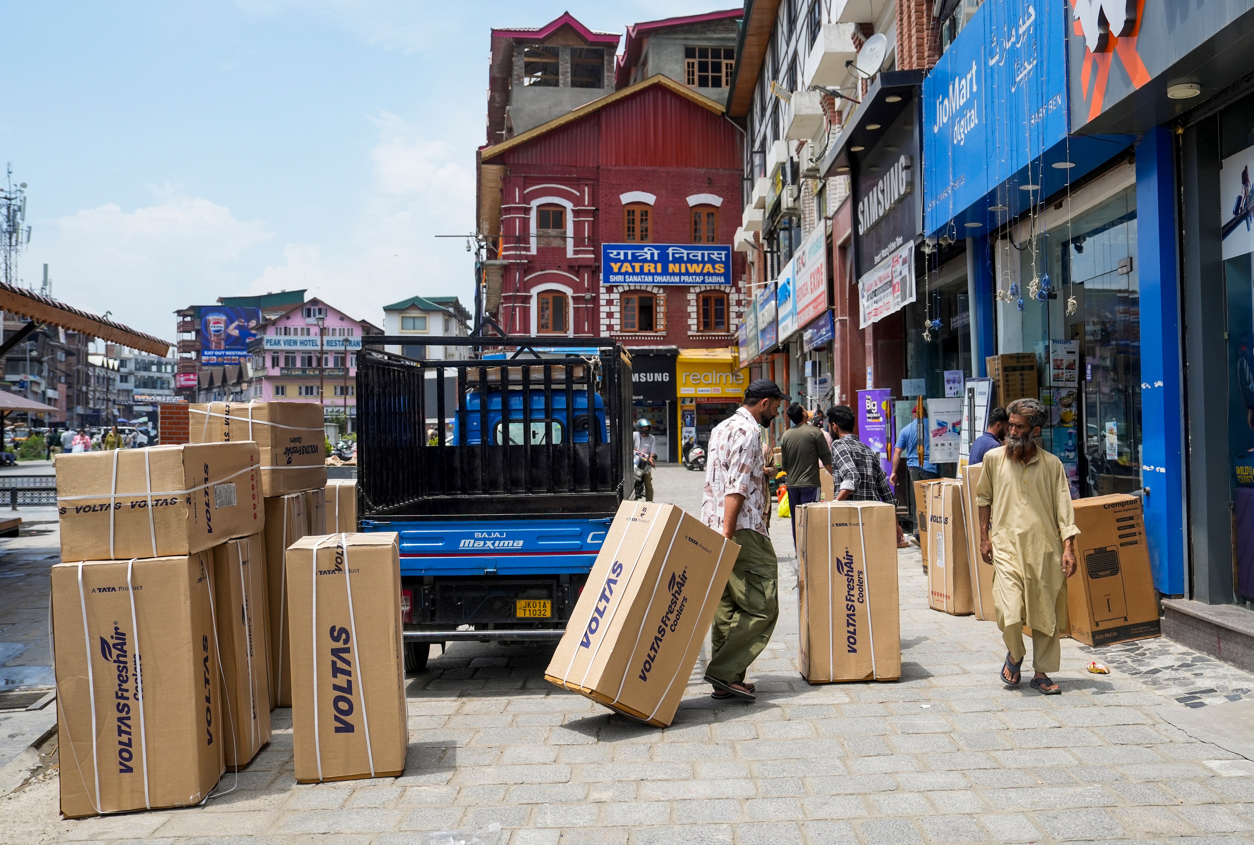  Labourers unload cooling appliances near a shop. (Photo: PTI)