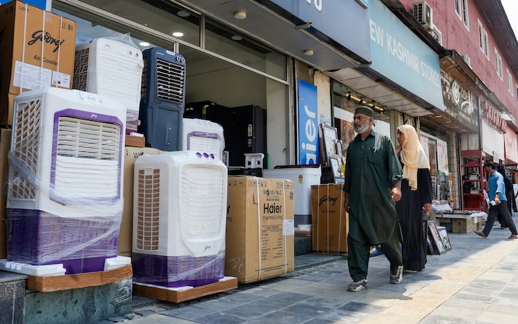 People walk past a shop selling cooling appliances during a heatwave. (Photo: PTI)