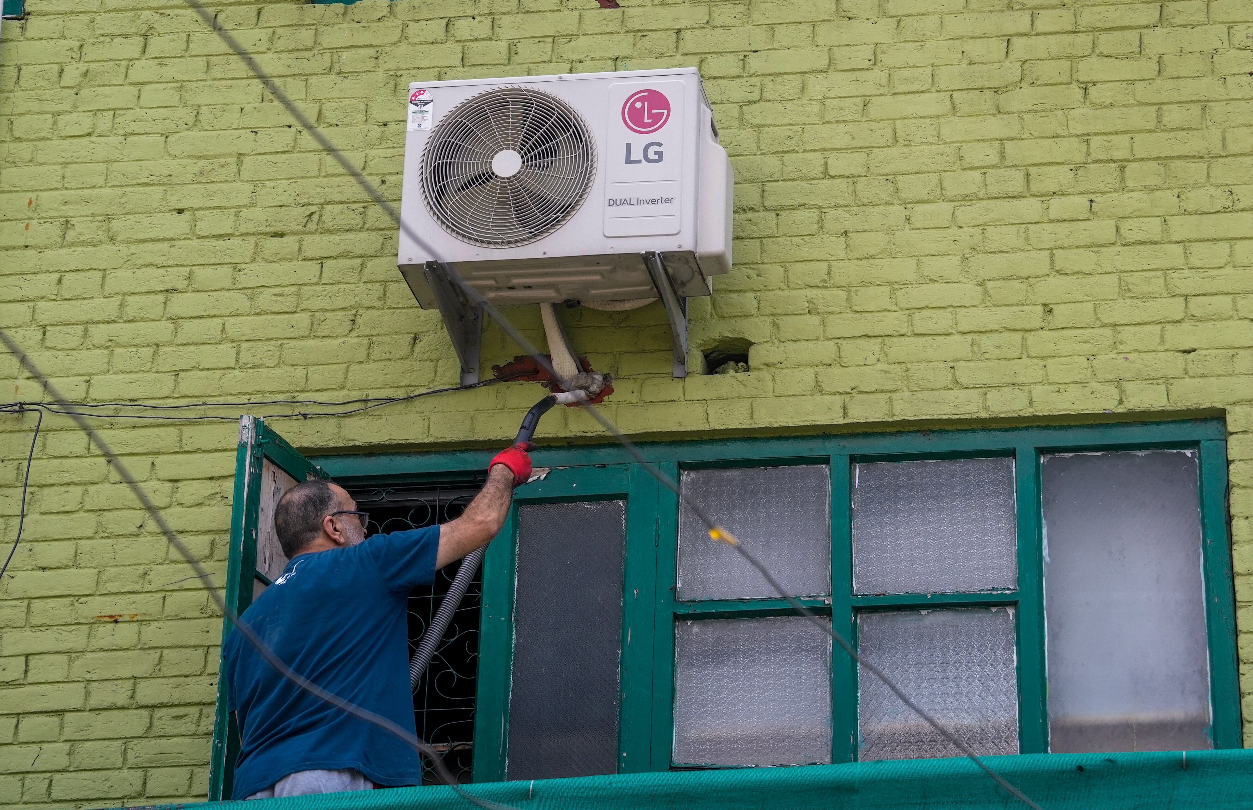 A technician repairs an air conditioner of a house in Srinagar. (Photo: PTI)