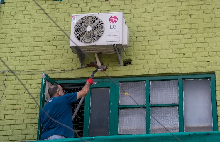 A technician repairs an air conditioner of a house in Srinagar. (Photo: PTI)