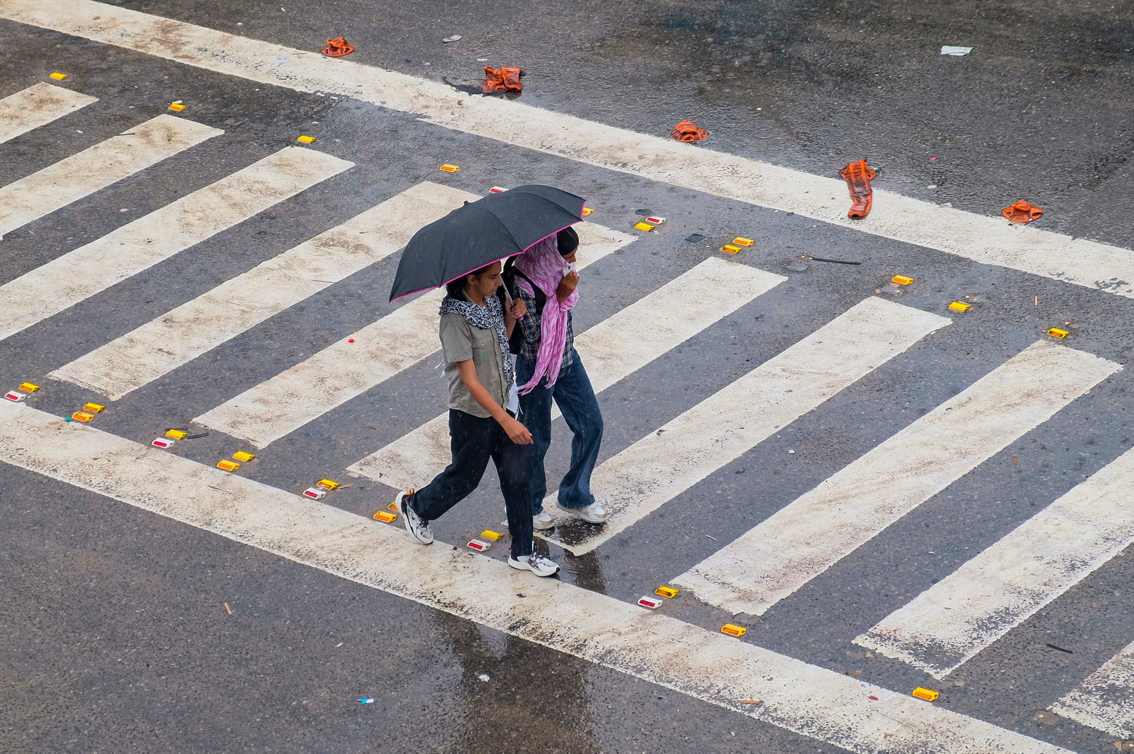 Commuters cross a zebra crossing amid rain. (Photo: PTI)