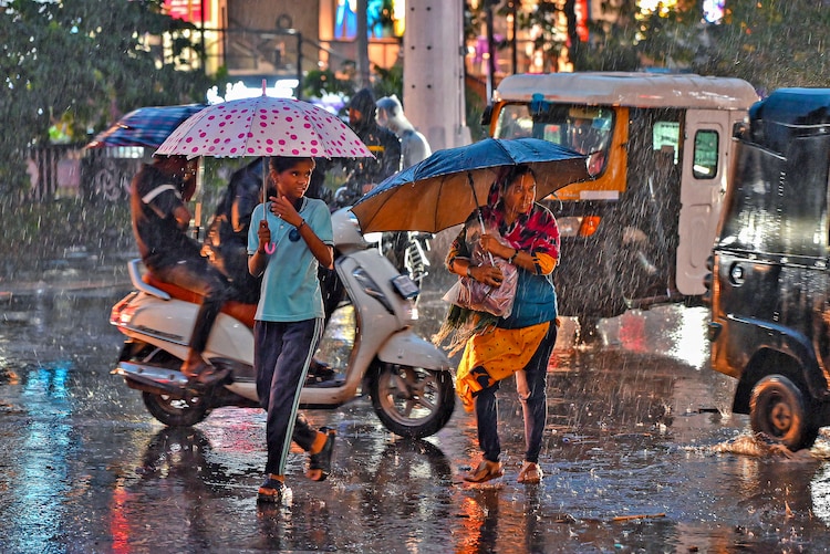 Commuters seek shelter amid rain, in Sangli, Maharashtra. (Photo: PTI)