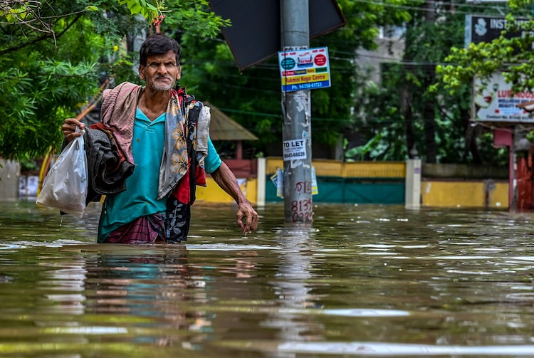 A man wades throguh a waterlogged street amid heavy rain. (Photo: Reuters)