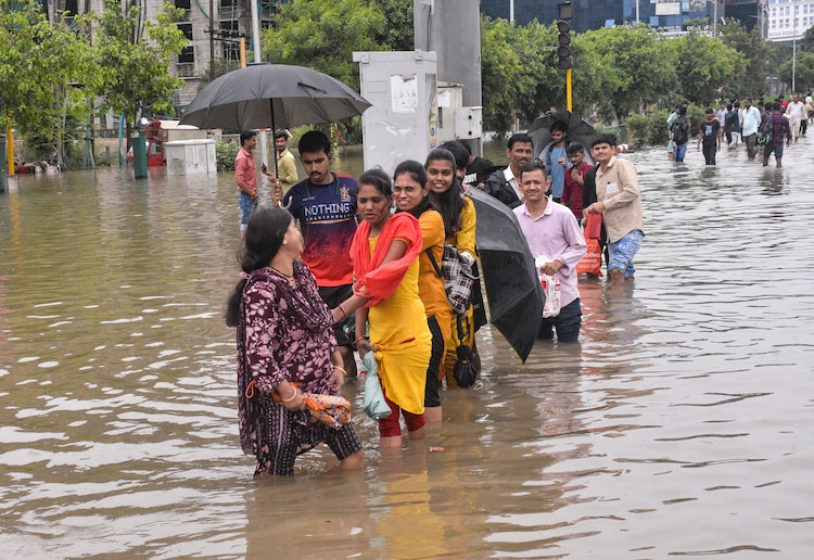 People wade through water-logged streets after heavy rainfall. (Photo: PTI))