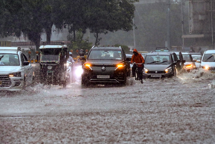 Vehicles wade through a waterlogged road following heavy rainfal. (Photo: PTI)