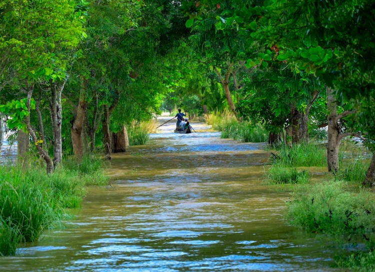 People use a boat to wade through a flood-affected area at Banki, Odisha. (Photo: PTI)