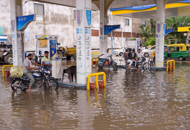 Commuters refuel their vehicles at a waterlogged petrol pump following rain. (Photo: PTI)