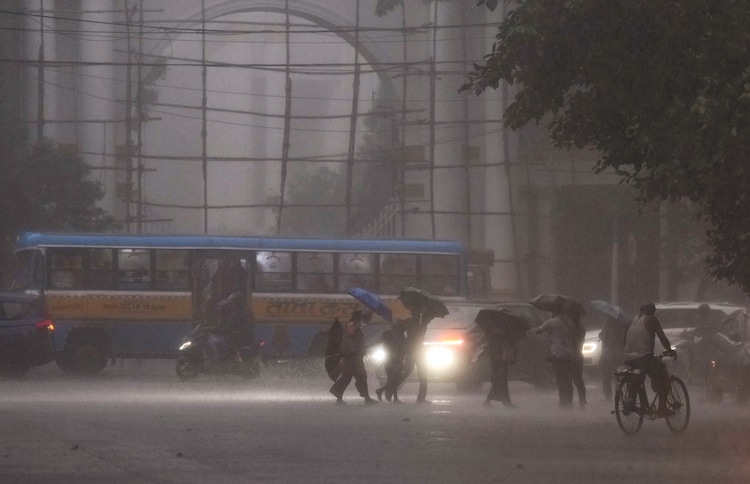 Vehicles move with headlights on as pedestrians wade through a road during heavy rain. (Photo: PTI)
