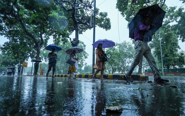 Commuters walk on a road amid heavy rain, in New Delhi. (Photo: PTI)