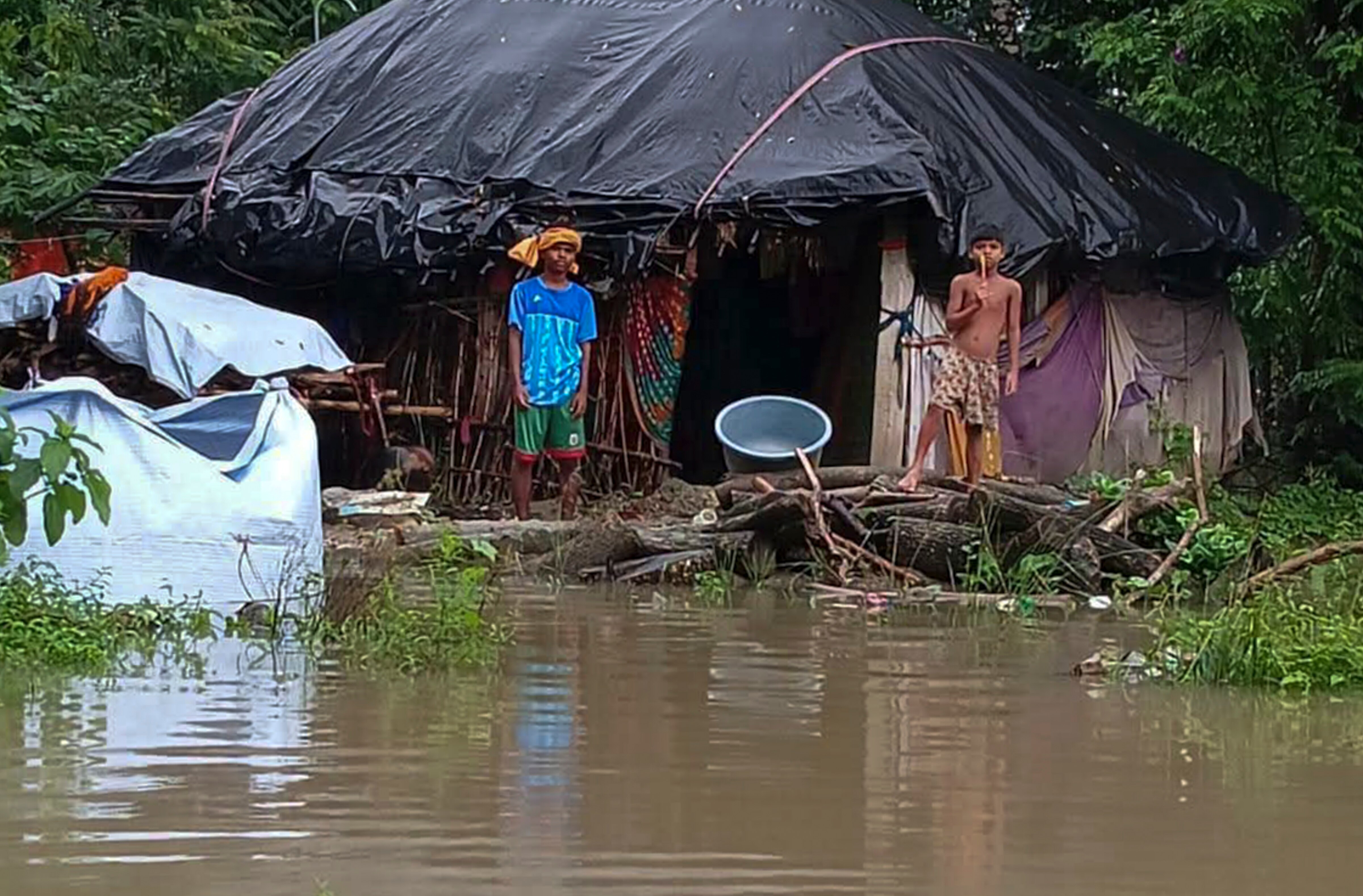 People of low-lying areas stand near their flooded homes following heavy rain. (Photo: PTI)