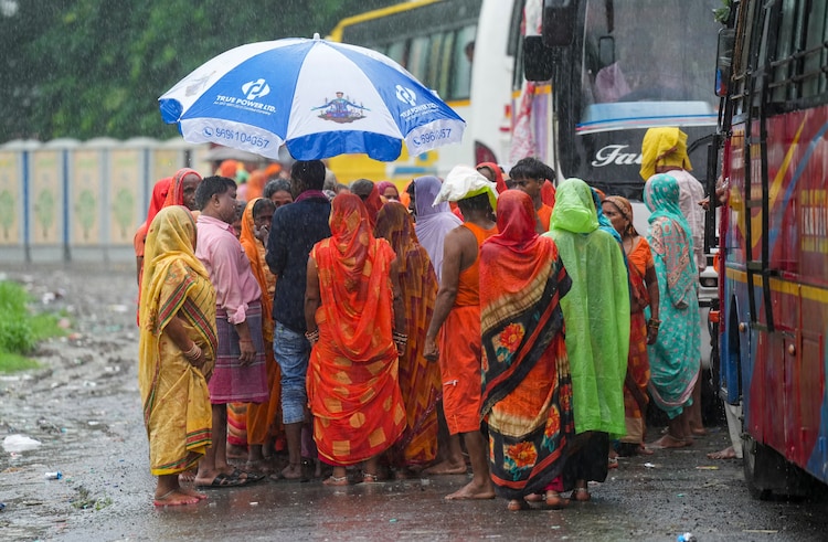 A group of devotees seek shelter during a monsoon rain shower. (Photo: PTI)