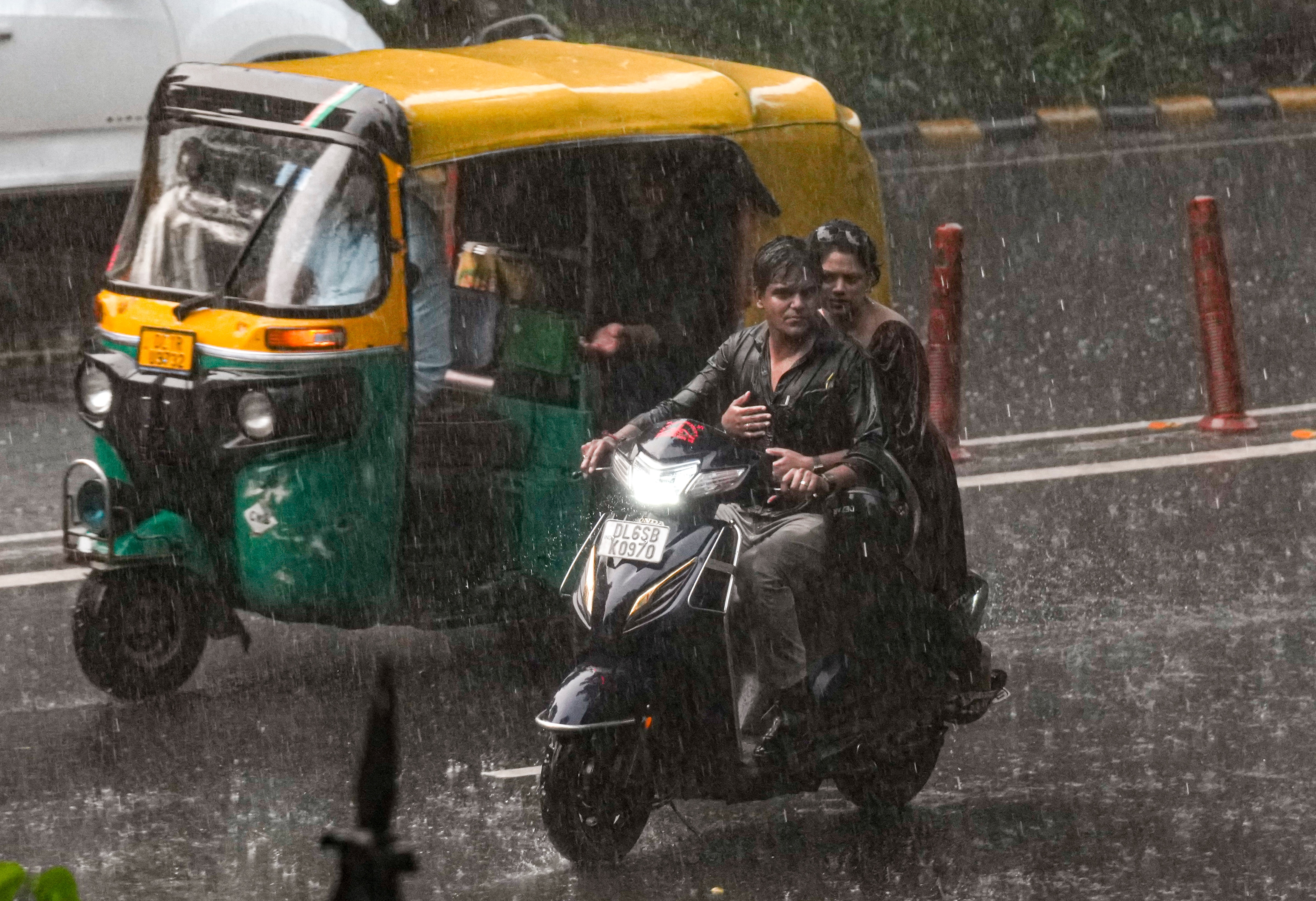 People commute through heavy rain during a monsoon downpour, in New Delhi. (Photo: PTI)