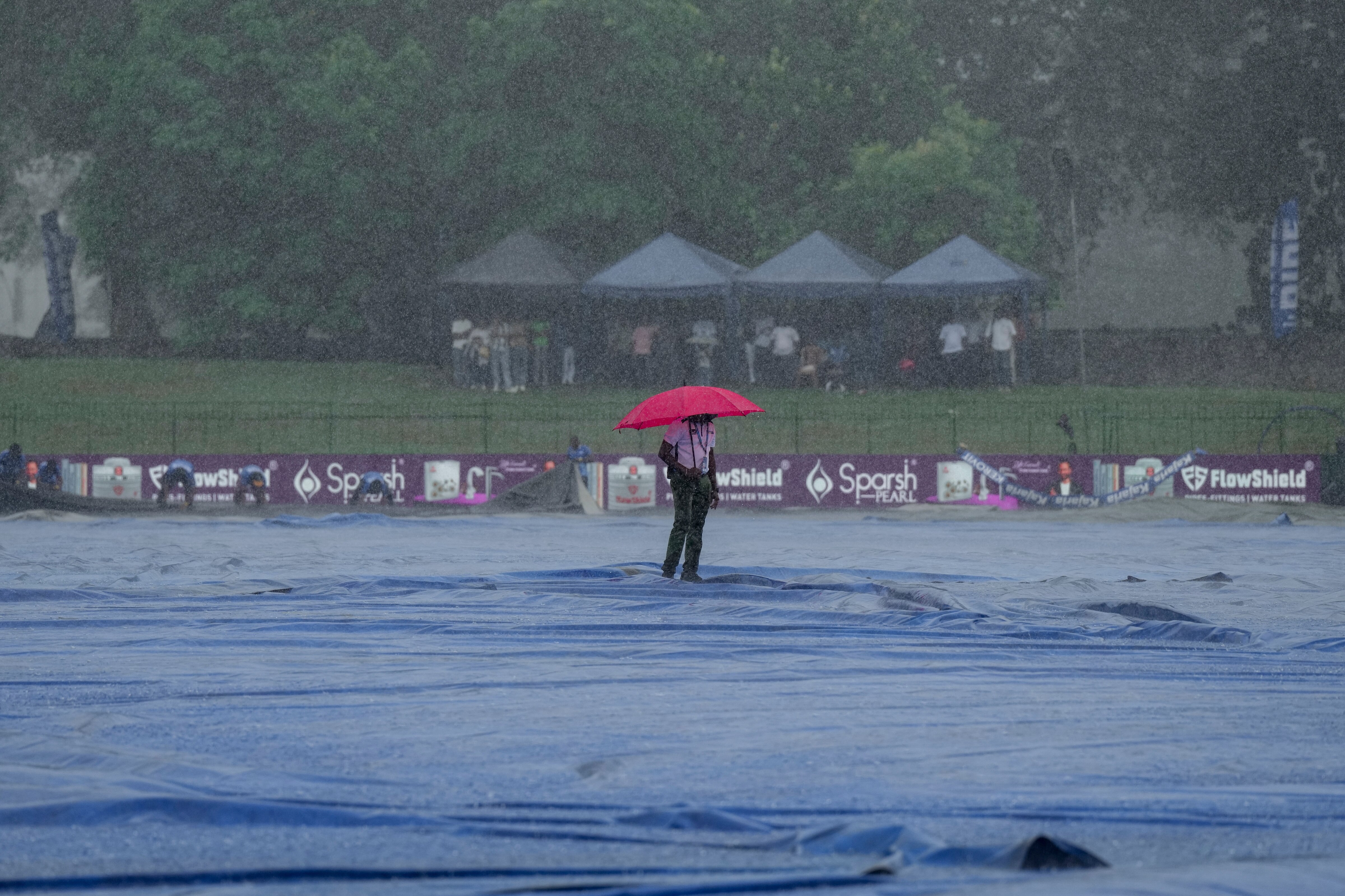 A man is seen inspecting a cricket pitch amid heavy rain. (Photo: PTI)