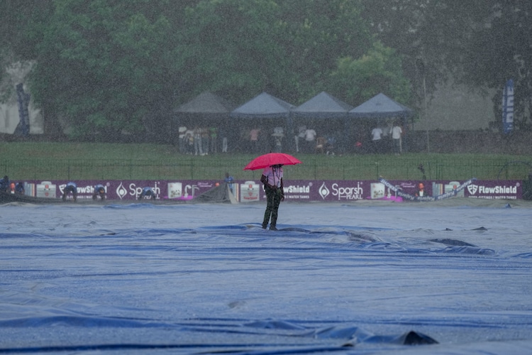A man is seen inspecting a cricket pitch amid heavy rain. (Photo: PTI)