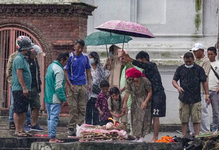 Family members perform rituals amid rain. (Photo: PTI)