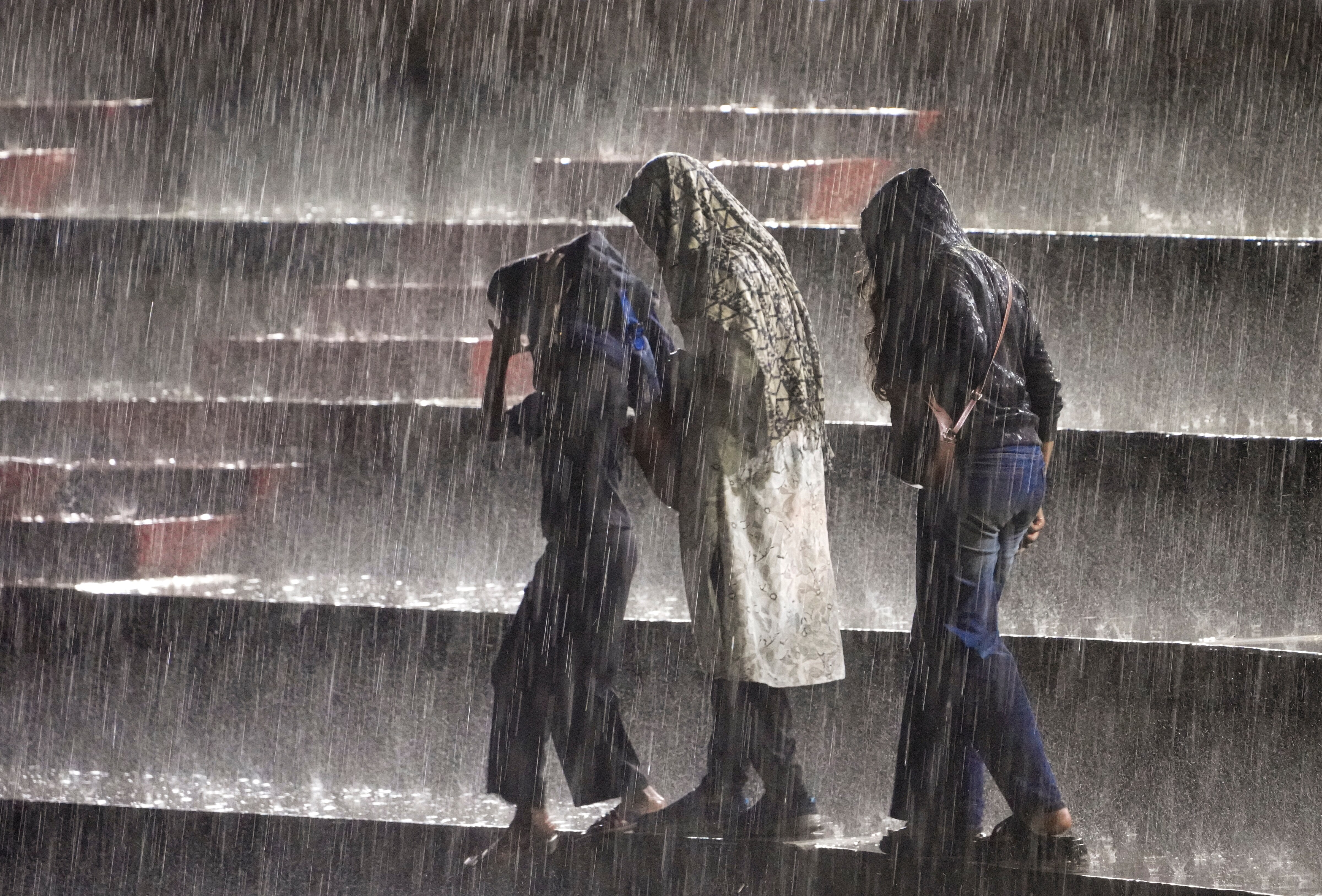 People shield themselves from the rain during heavy rain showers. (Photo: PTI)