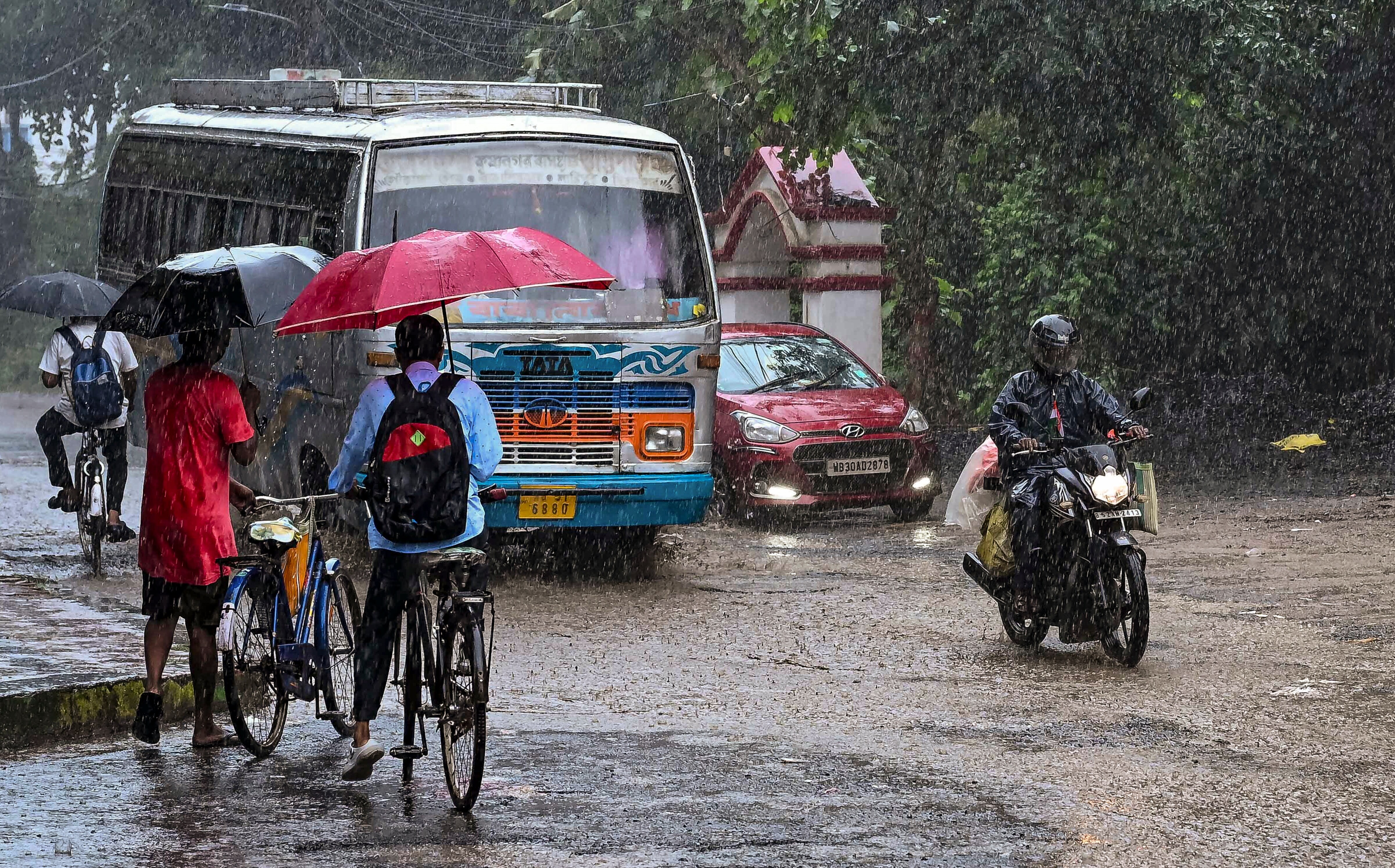 Commuters move on a street amid rain. (Photo: PTI)