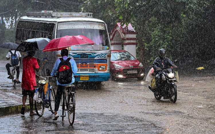 Commuters move on a street amid rain. (Photo: PTI)