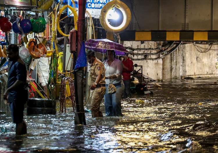 People move on a waterlogged road following rain, in Mumbai. (Photo: PTI)