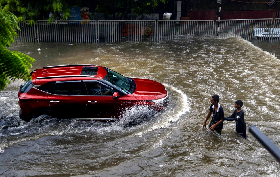 Vehicles wade through a waterlogged road following heavy rainfal. (Photo: PTI)