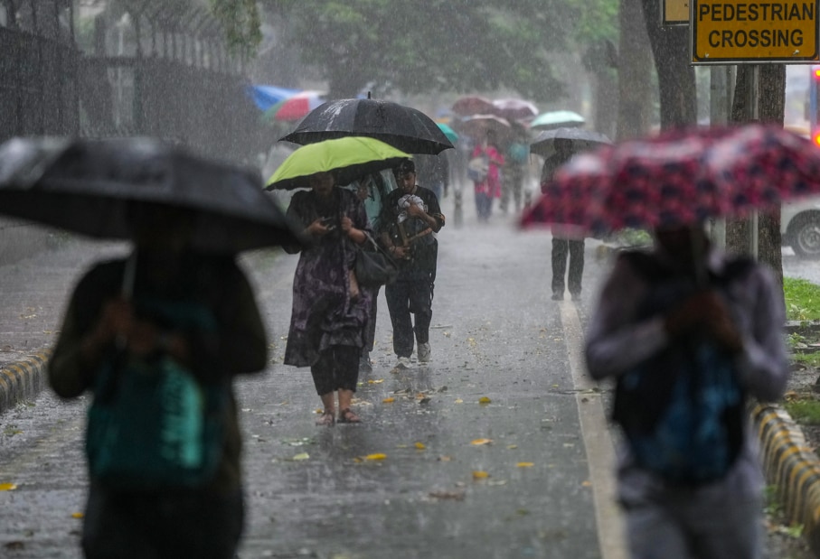 People cover themselves as they walk amid rainfall. (Photo: PTI)