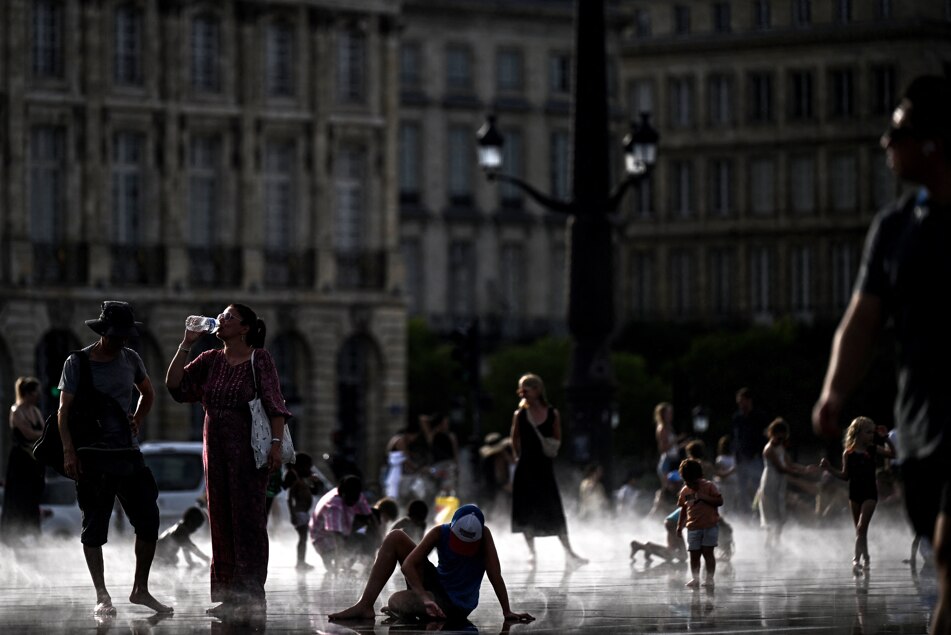 A pedestrian drinks water on the reflecting pool amid a heatwave in France. (Photo: AFP)