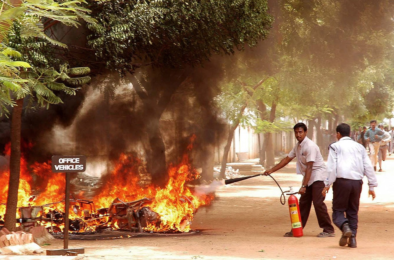 Security personnel and bystanders battle flames outside Dinakaran office in Madurai after a violent political attack, May 9, 2007. (Photo: AFP)