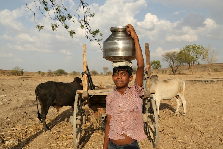 A boy carries water from a well during a hot day in Dhule, Maharashtra. (Photo: Unsplash)