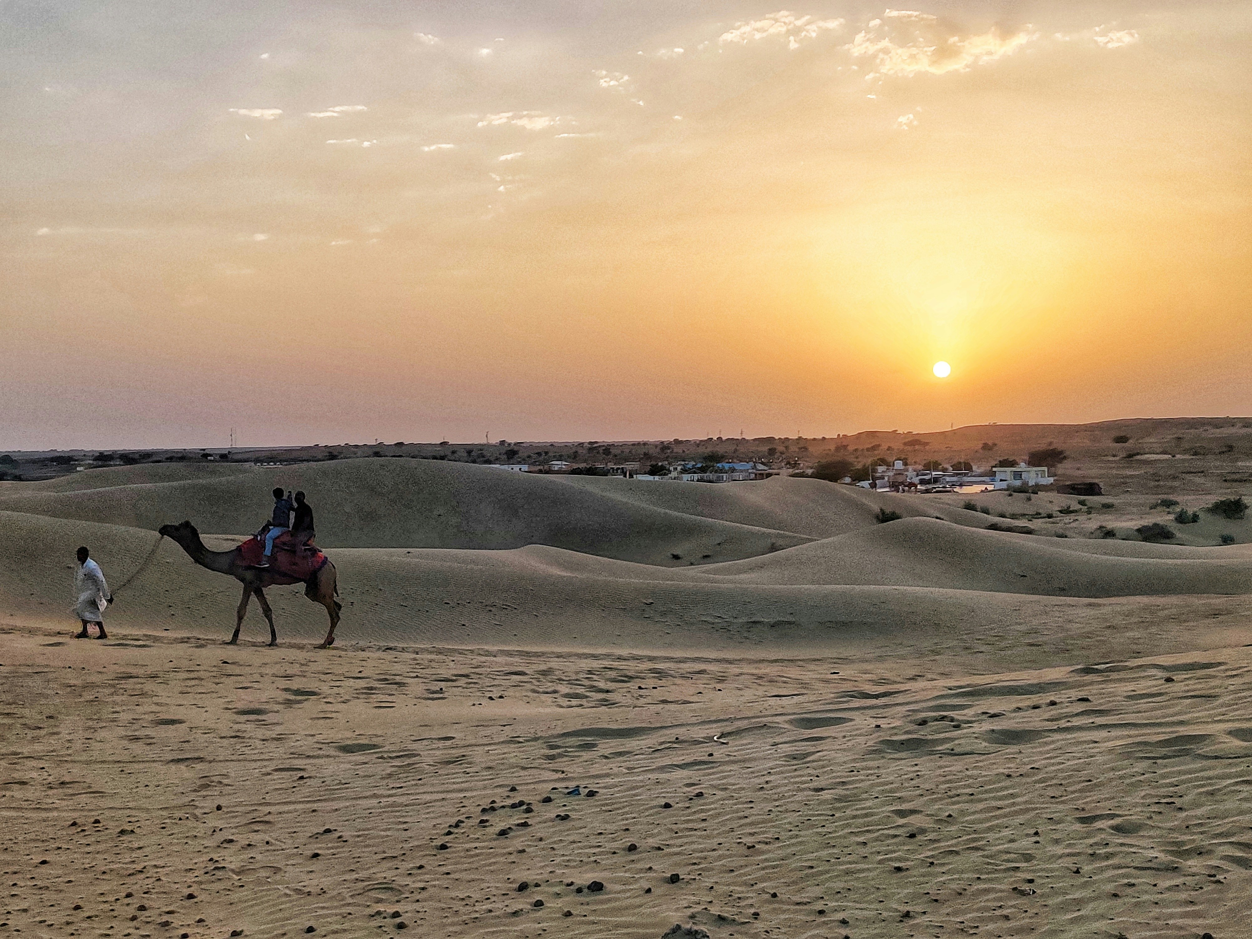 A view of a man walking a camel near a sand dune in Jaisalmer, Rajasthan. (Photo: Unsplash)