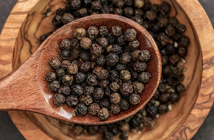 Black peppercorns are seen in a wooden spoon. (Photo: Pexels)
