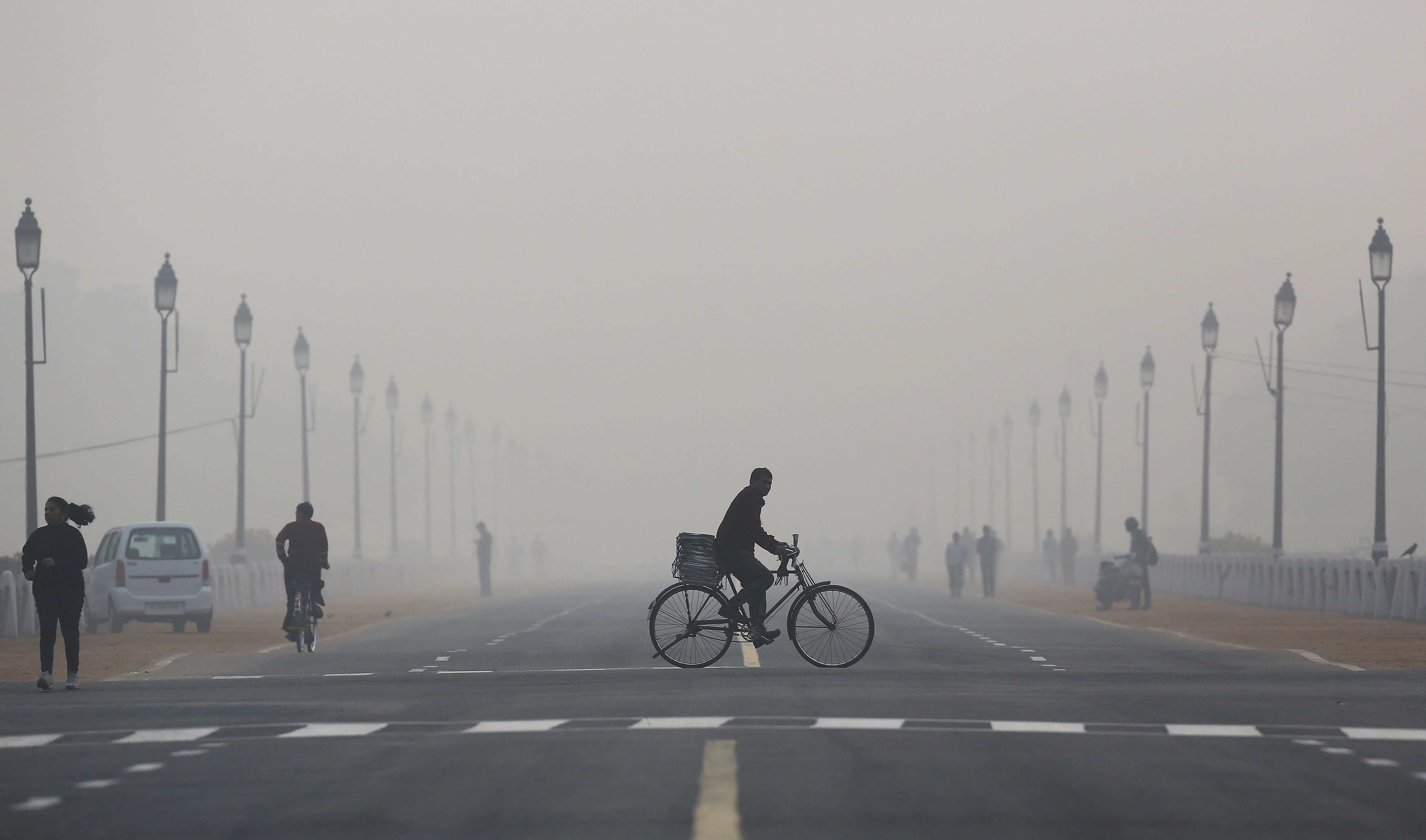 People cycle, run and walk through thick smog in Delhi. The city recorded zero clean-air days in 2025, making it one of the most persistently polluted capitals in the world. (Photo: Reuters)