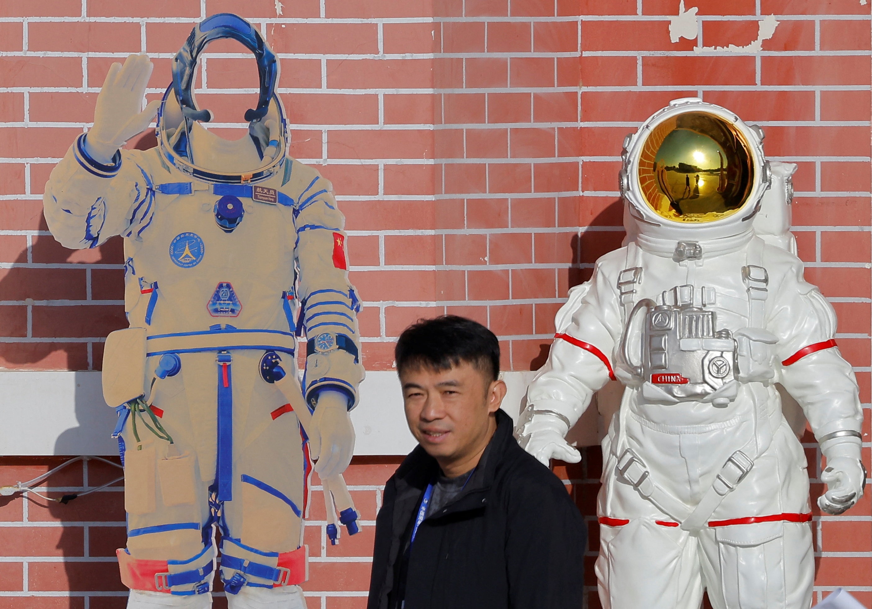 A man walks past figures of spacesuits before the start of Shenzhou-21 spaceflight mission at the Jiuquan Satellite Launch Center. (Photo: Reuters)