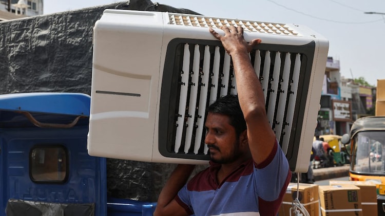 A worker carries an air cooler for delivery to a customer during the heatwave in Ahmedabad. (Photo: Reuters)