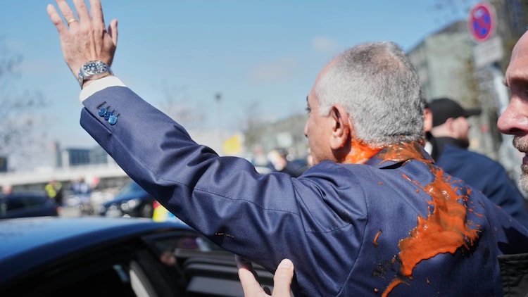 Reza Pahlavi waves to supporters after he was attacked with a red fluid following a news conference in Berlin, Germany