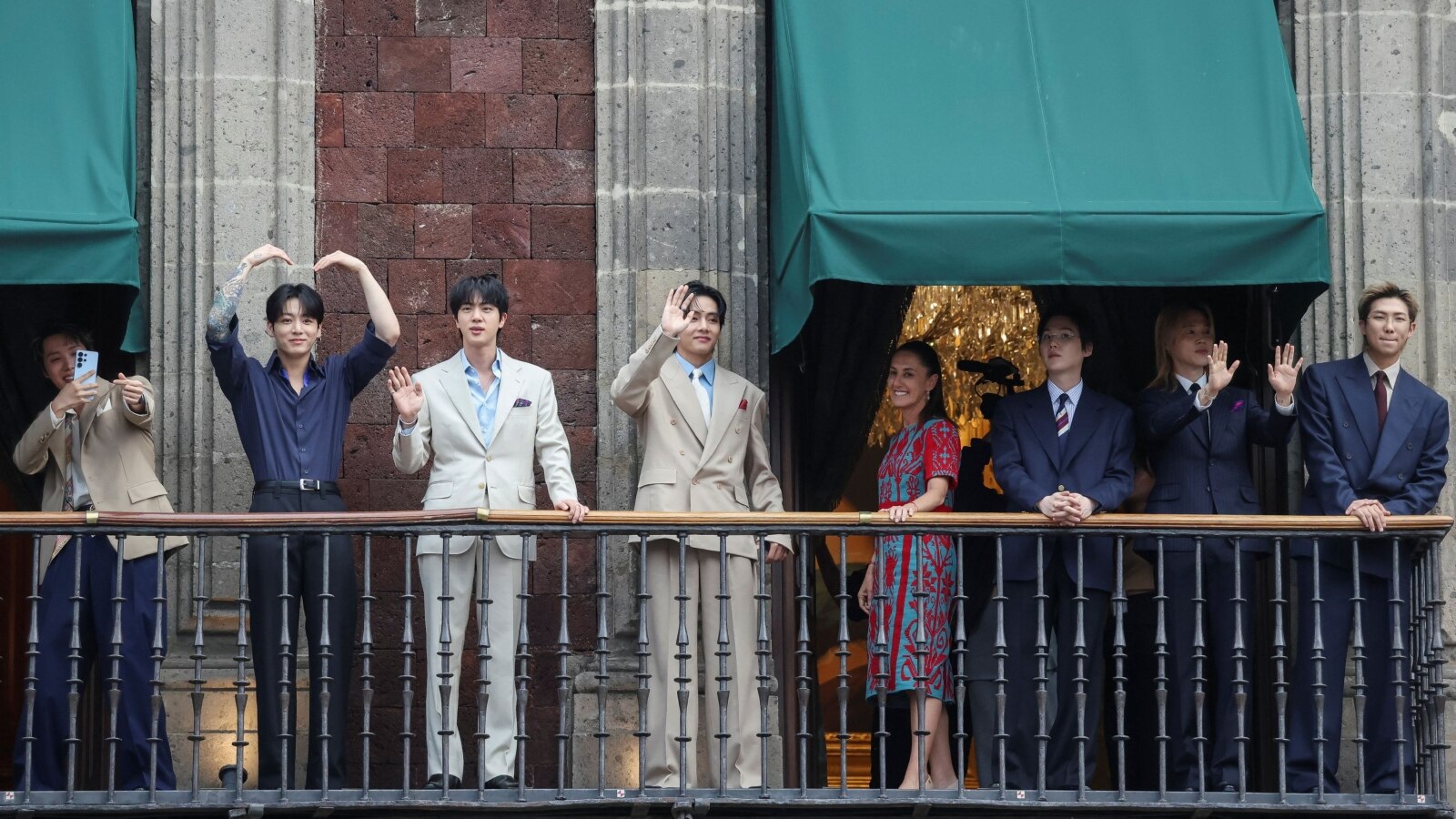 Mexico's President Claudia Sheinbaum and members of South Korean Kpop boy band BTS react as they stand on a balcony of the National Palace ahead of a series of concerts on the BTS World Tour 