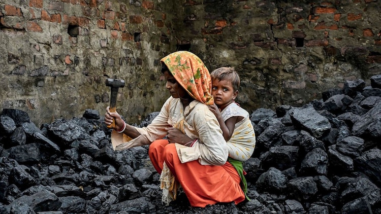 A woman labourer, who works in a coal mine, is holding her baby. (Photo: PTI)