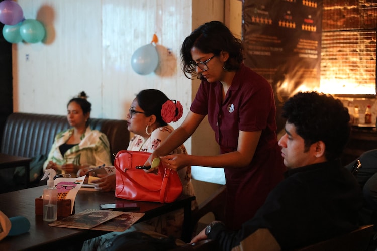 Pint of Science 2026, Delhi. Between sessions, the questions started coming faster than anyone anticipated. The Pint of Science booklet on the table, the balloons on the wall, and a bar that had not yet settled into the particular hum it would find later in the night.