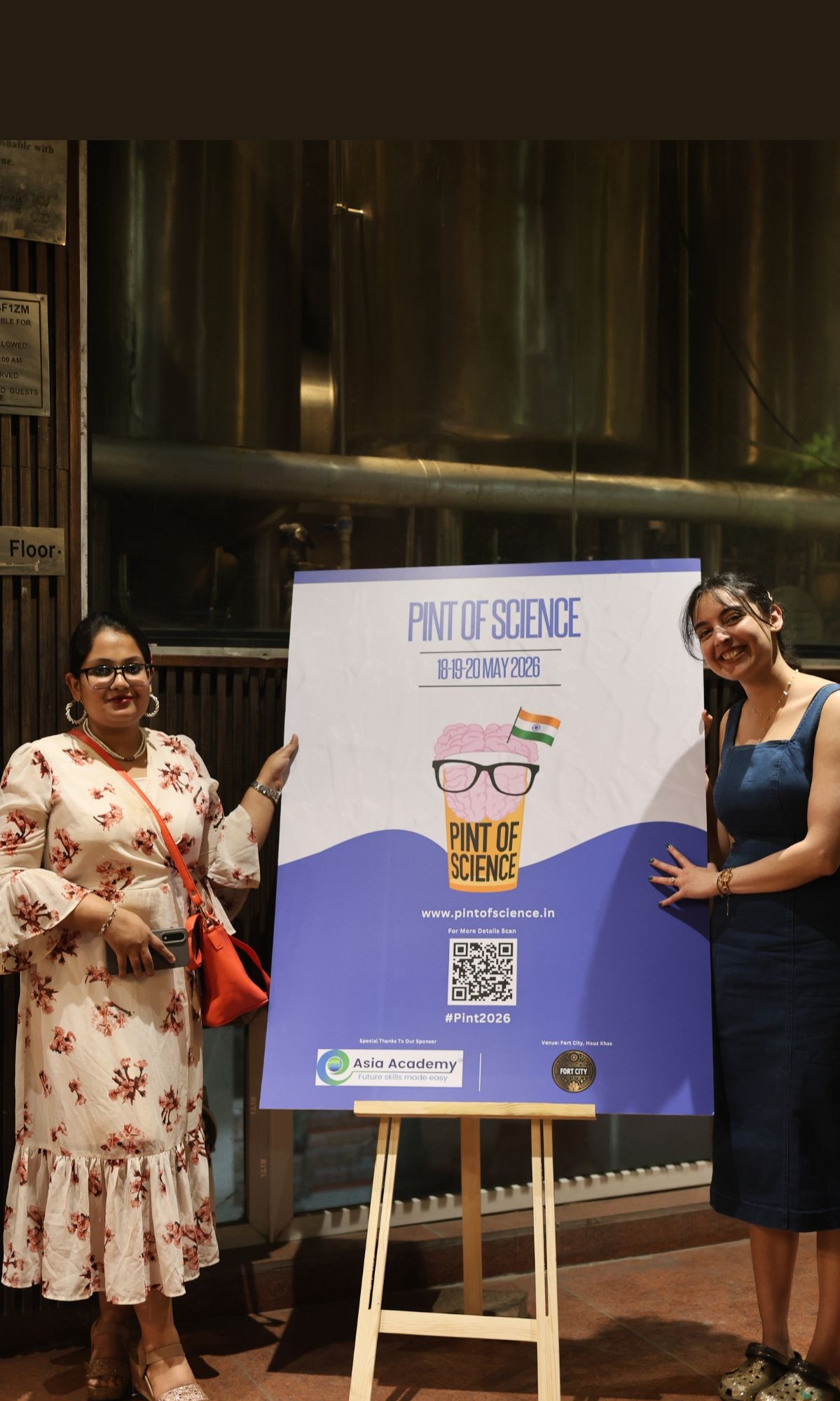 Me with Dr Pratiksha Nagar, homeopath and researcher at University College Dublin, outside Fort City Brewing, Hauz Khas, at Pint of Science 2026. Dr Nagar spent the evening explaining why predicting the next pandemic means watching a cow's milk yield. The audience found this considerably more alarming than expected.