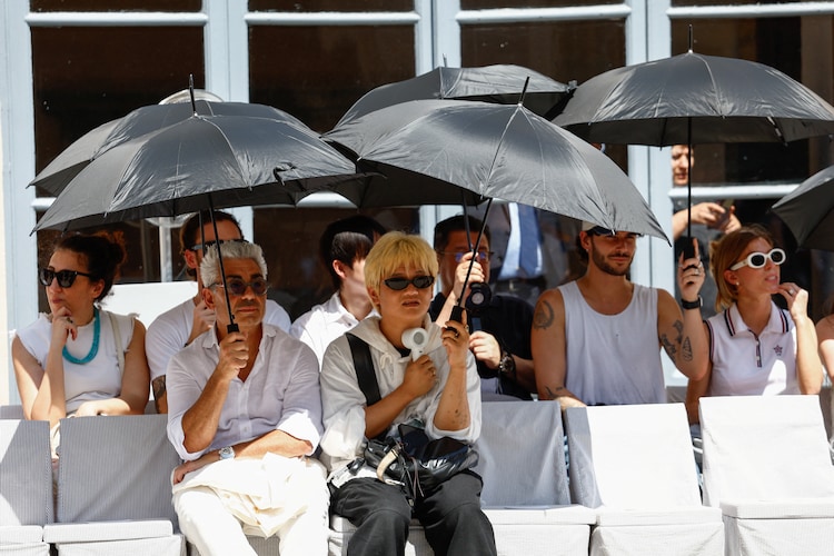 People shield themselves with umbrellas from the sun during Thom Browneâs Spring/Summer 2027 menâs collection show in Milan, Italy.