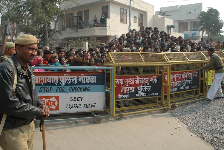 Police use barricades to restrain people who gathered as they recover bodies of children, unseen, in Noida, UP, Saturday, Dec. 30, 2006. Indian police said Saturday they have discovered 15 skulls at a house near New Delhi where a domestic servant has confessed to sexually assaulting and killing children and women