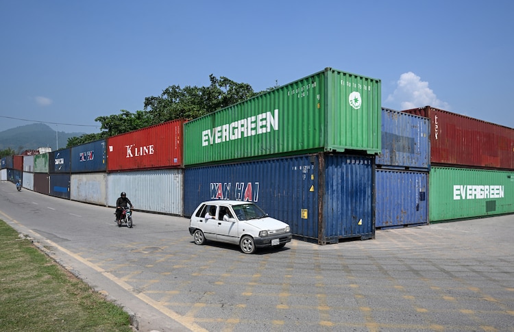 Commuters ride past shipping containers placed around Islamabad's Red Zone. (AFP Image)